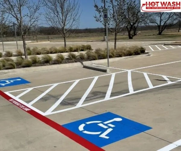Newly painted white parking stall lines, diagonal safety hash marks, and blue handicapped symbols freshly striped on a concrete commercial parking lot.